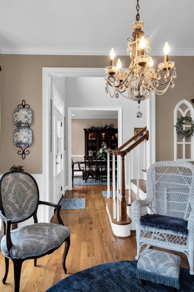 foyer featuring stairs, ornamental molding, wood finished floors, and an inviting chandelier