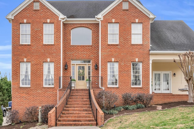 view of front of house with french doors, roof with shingles, and brick siding