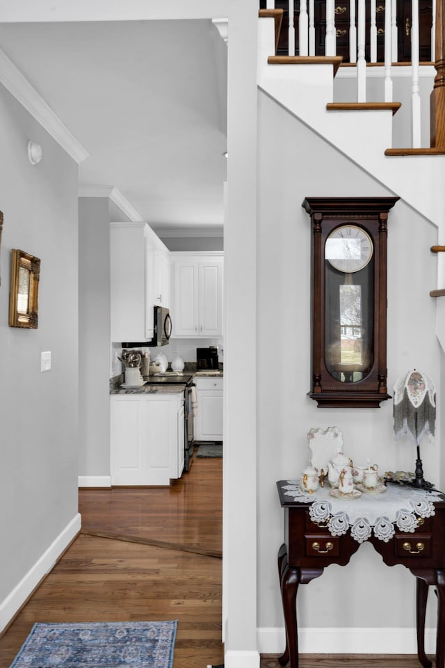 interior space featuring ornamental molding, dark wood-style flooring, stairway, and baseboards