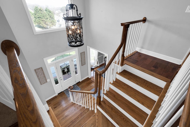 foyer with a chandelier, wood finished floors, a towering ceiling, baseboards, and stairway