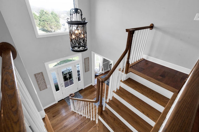 foyer featuring a towering ceiling, an inviting chandelier, wood finished floors, baseboards, and stairs