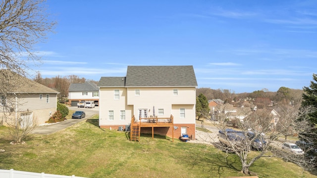 rear view of property featuring a shingled roof, a lawn, stairway, fence, and a deck