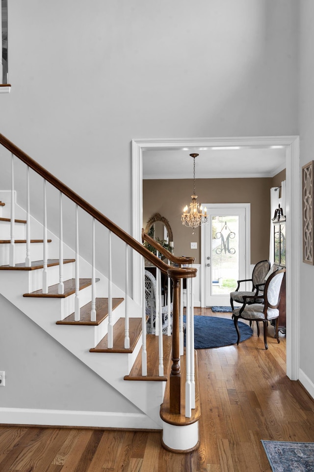 foyer with baseboards, stairway, a chandelier, and wood finished floors