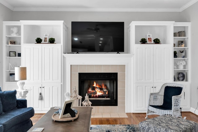 living room with a tiled fireplace, ornamental molding, and wood finished floors