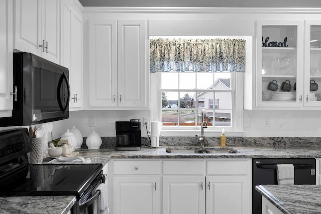 kitchen with a sink, white cabinetry, decorative backsplash, black appliances, and glass insert cabinets