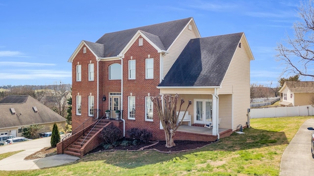 view of front of home with a front yard, french doors, brick siding, and fence