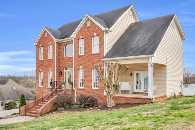 view of front of property with a patio, french doors, roof with shingles, and a front yard