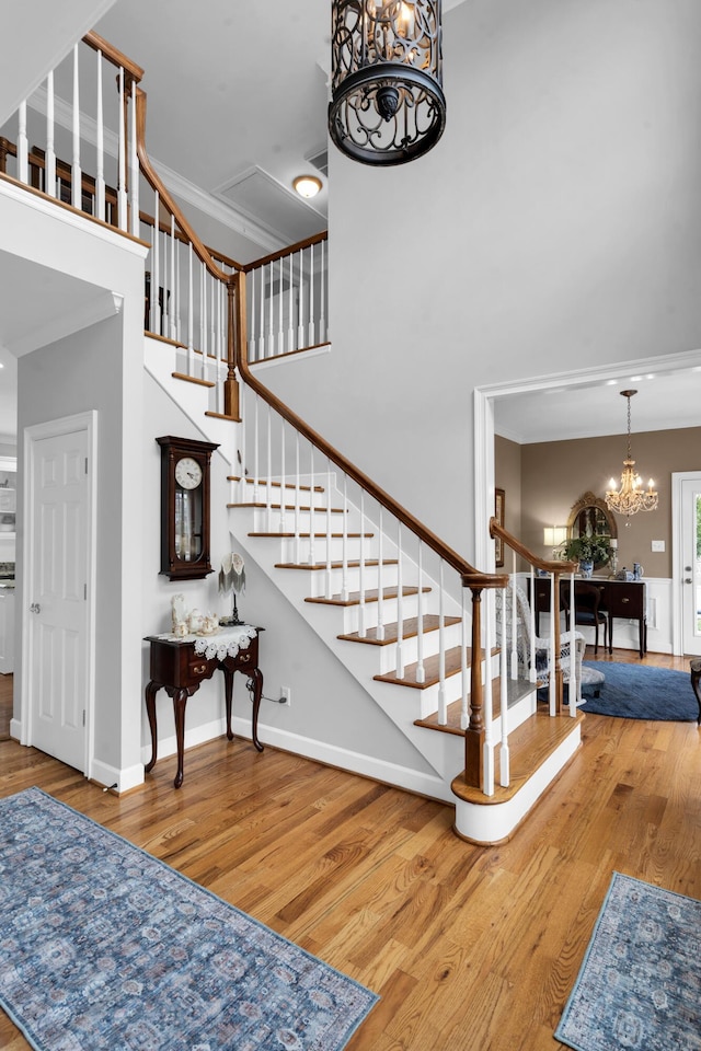 stairway featuring a notable chandelier, a high ceiling, wood finished floors, and baseboards