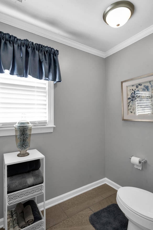 bathroom with crown molding, toilet, and baseboards