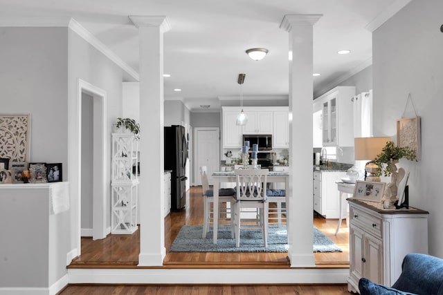 interior space with crown molding, ornate columns, and wood finished floors