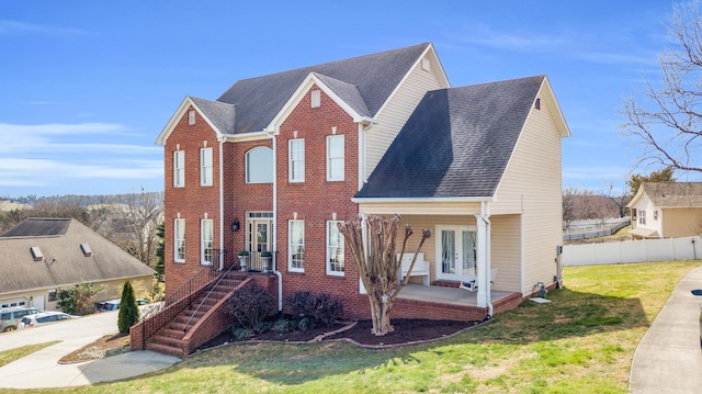 view of front facade featuring a front yard, french doors, brick siding, and fence