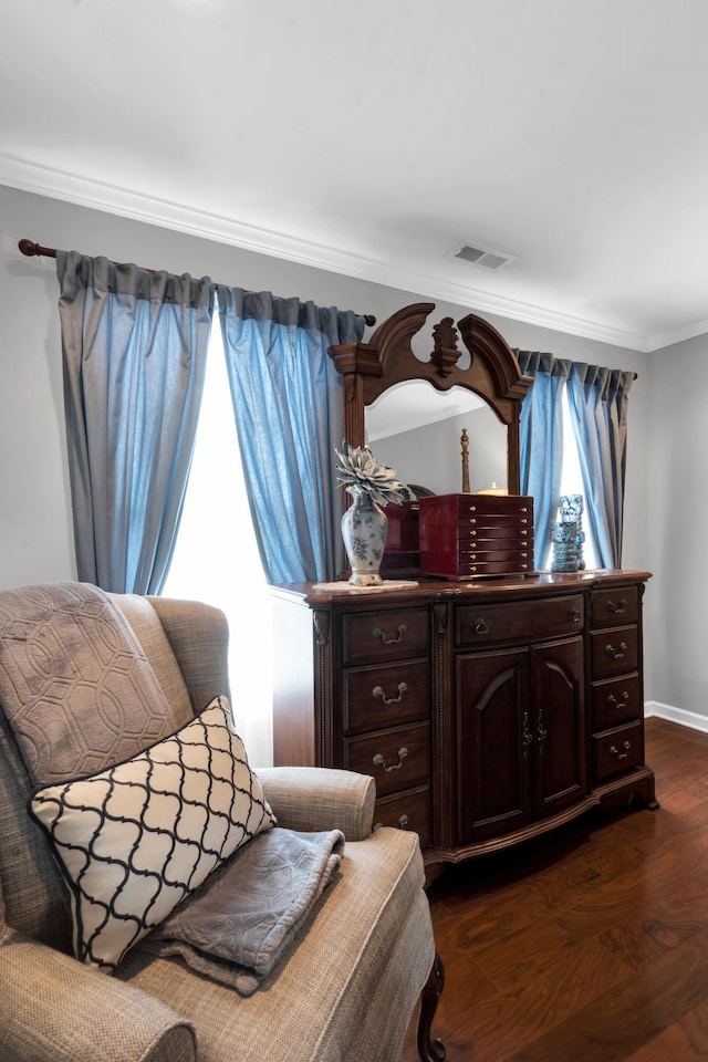 living area with ornamental molding, visible vents, dark wood finished floors, and baseboards