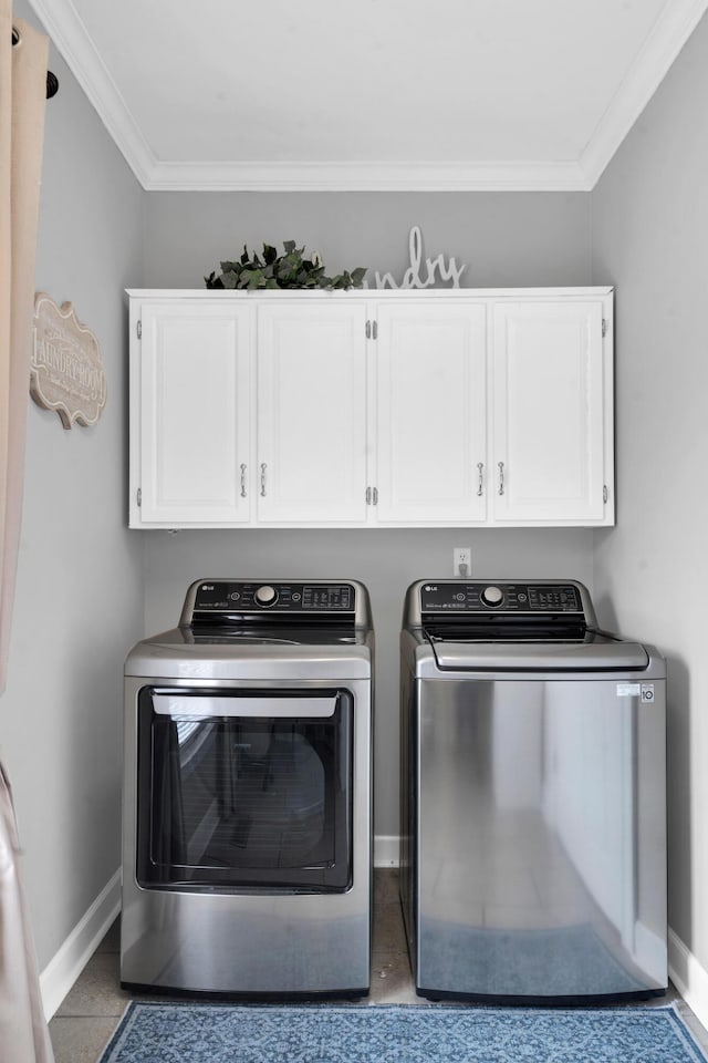 washroom featuring cabinet space, baseboards, crown molding, and washing machine and clothes dryer