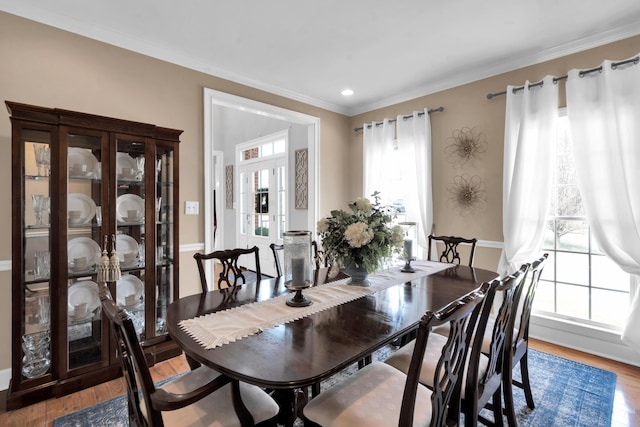 dining space featuring light wood-style flooring and ornamental molding