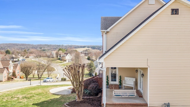 view of side of property with a shingled roof and a porch