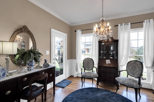 sitting room featuring ornamental molding, wainscoting, a notable chandelier, and wood finished floors