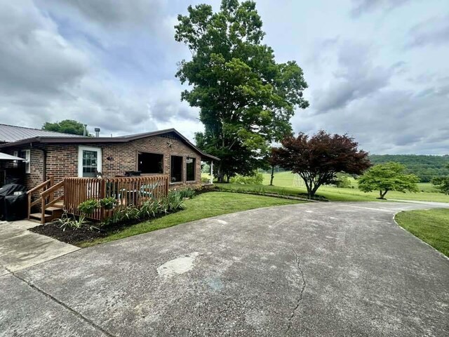 2996 Sugar Grove Valley Rd, Harriman, TN 37748 - view of side of home with a yard, a deck, brick siding, and concrete driveway