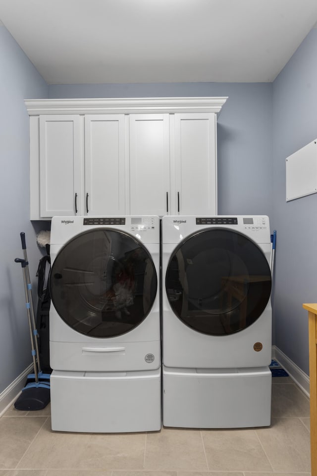 washroom featuring washer and dryer, light tile patterned flooring, and cabinets