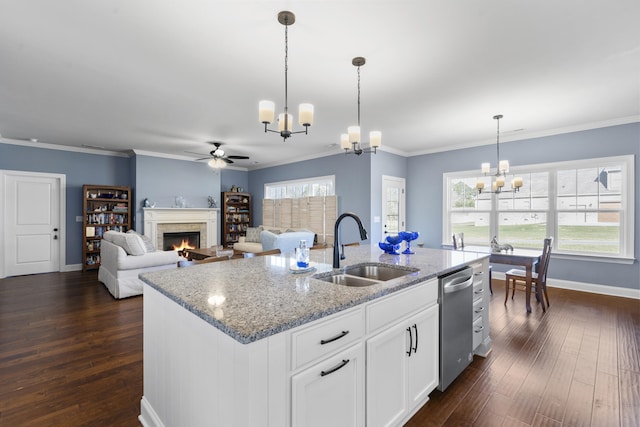 kitchen featuring white cabinetry, sink, light stone counters, pendant lighting, and a center island with sink