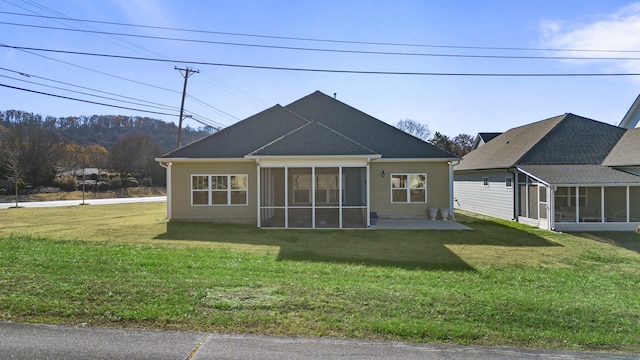 rear view of property featuring a patio, a lawn, and a sunroom