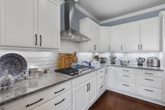 kitchen featuring white cabinets, wall chimney exhaust hood, backsplash, and stainless steel gas stovetop