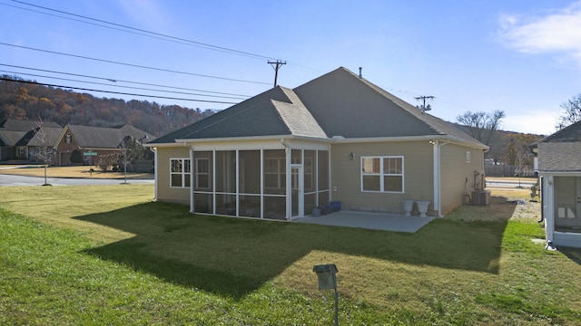 rear view of house featuring a lawn, a sunroom, a patio, and central AC