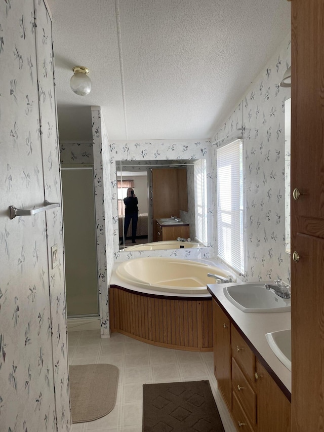 bathroom with vanity, a textured ceiling, and shower with separate bathtub