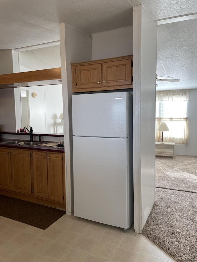 kitchen featuring a textured ceiling, white fridge, and sink