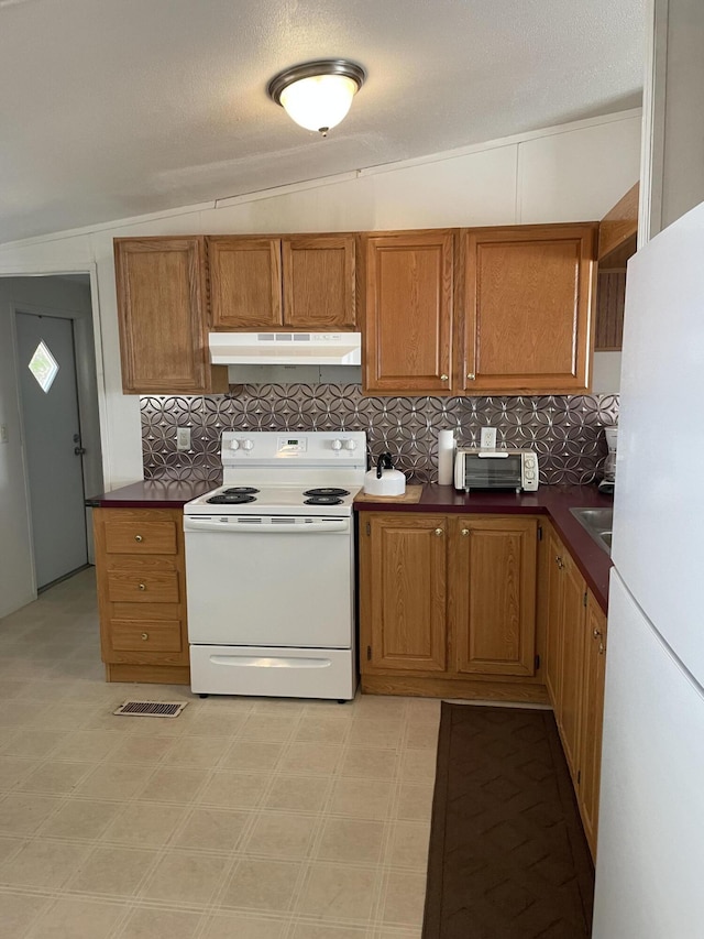 kitchen with white appliances, lofted ceiling, and backsplash