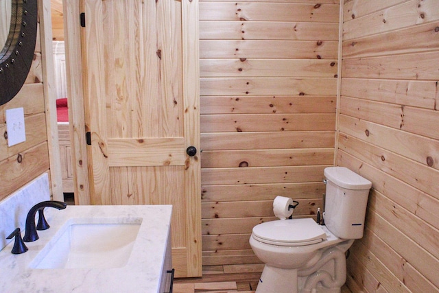 bathroom featuring wooden walls, vanity, and toilet