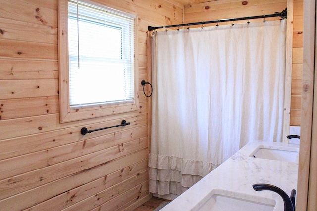 bathroom featuring a sink, wooden walls, and curtained shower