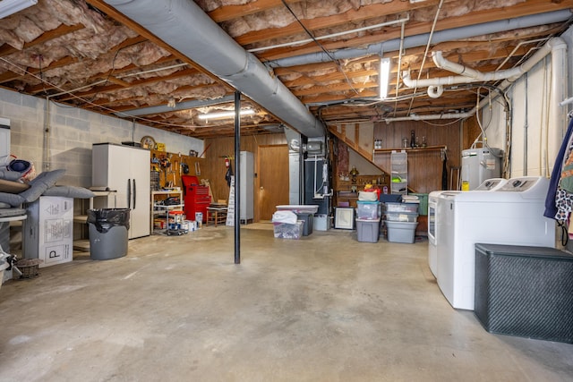 unfinished below grade area featuring concrete block wall, electric water heater, freestanding refrigerator, and separate washer and dryer