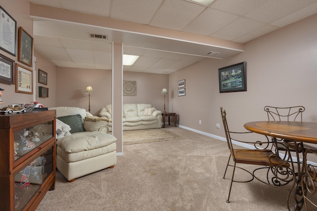 carpeted living room with visible vents, baseboards, and a drop ceiling