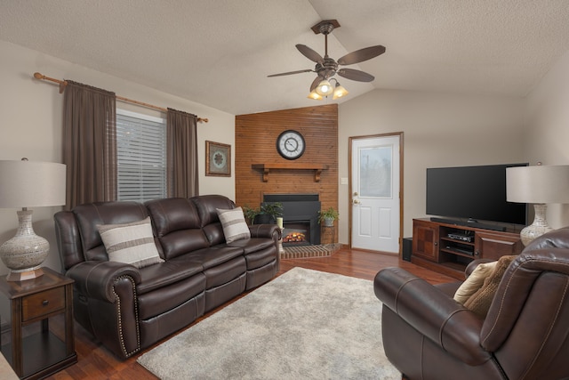 living area featuring dark wood-type flooring, a brick fireplace, ceiling fan, and vaulted ceiling