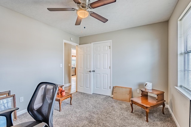 carpeted home office with a textured ceiling, ceiling fan, and baseboards