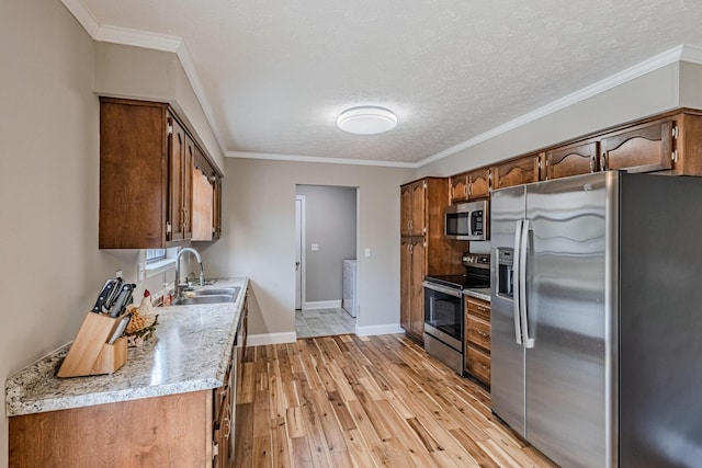 kitchen featuring independent washer and dryer, light countertops, stainless steel appliances, light wood-type flooring, and a sink