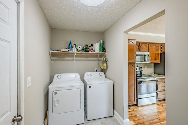 laundry room with a textured ceiling, washing machine and dryer, laundry area, baseboards, and light wood-type flooring