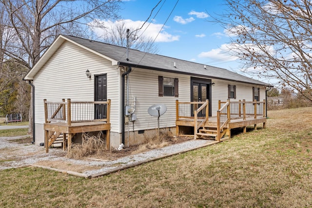 rear view of property featuring crawl space, a deck, and a yard