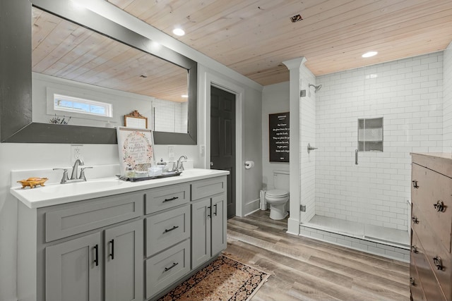 bathroom featuring hardwood / wood-style floors, vanity, toilet, and a tile shower