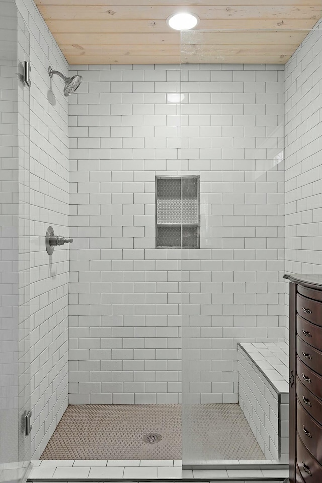 bathroom featuring a tile shower and wood ceiling