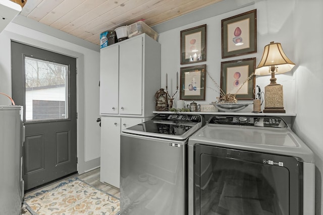 clothes washing area with cabinets, light hardwood / wood-style floors, wooden ceiling, and washing machine and clothes dryer