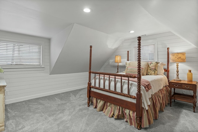 carpeted bedroom with multiple windows, lofted ceiling, and wood walls