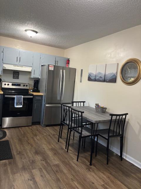 kitchen with a textured ceiling, stainless steel appliances, extractor fan, and dark hardwood / wood-style floors