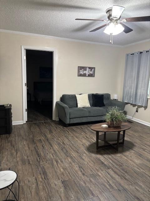 living room with dark hardwood / wood-style flooring, a textured ceiling, ceiling fan, and ornamental molding