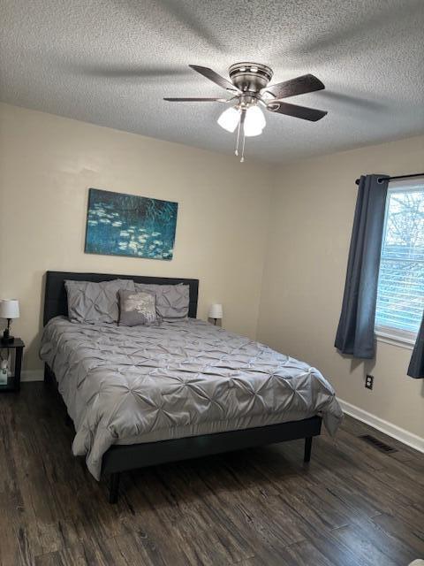 bedroom with a textured ceiling, dark hardwood / wood-style floors, and ceiling fan