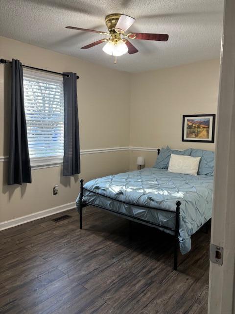 bedroom featuring a textured ceiling, dark hardwood / wood-style flooring, and ceiling fan