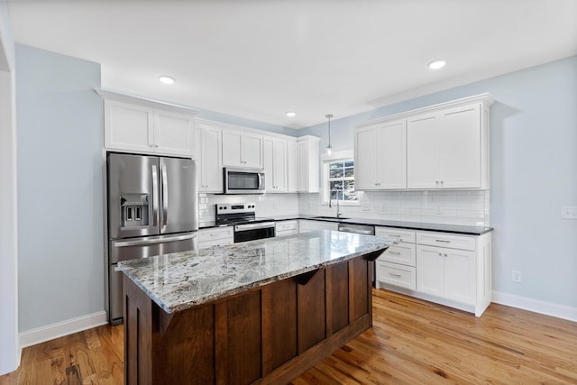 605 Westover Dr SW, Cleveland, TN 37311 - kitchen featuring appliances with stainless steel finishes, light wood-style floors, white cabinetry, decorative backsplash, and a center island