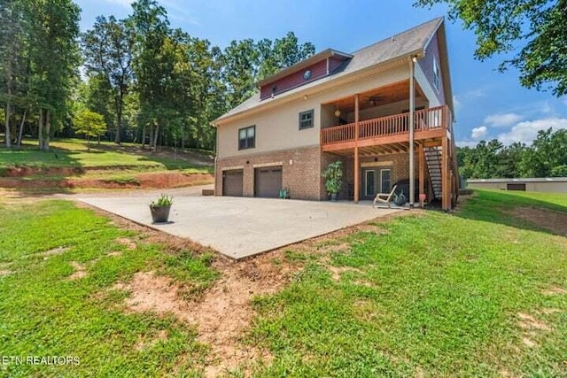 rear view of property with a deck, a yard, and a garage