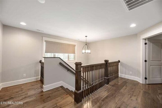 stairs with hardwood / wood-style flooring and a chandelier