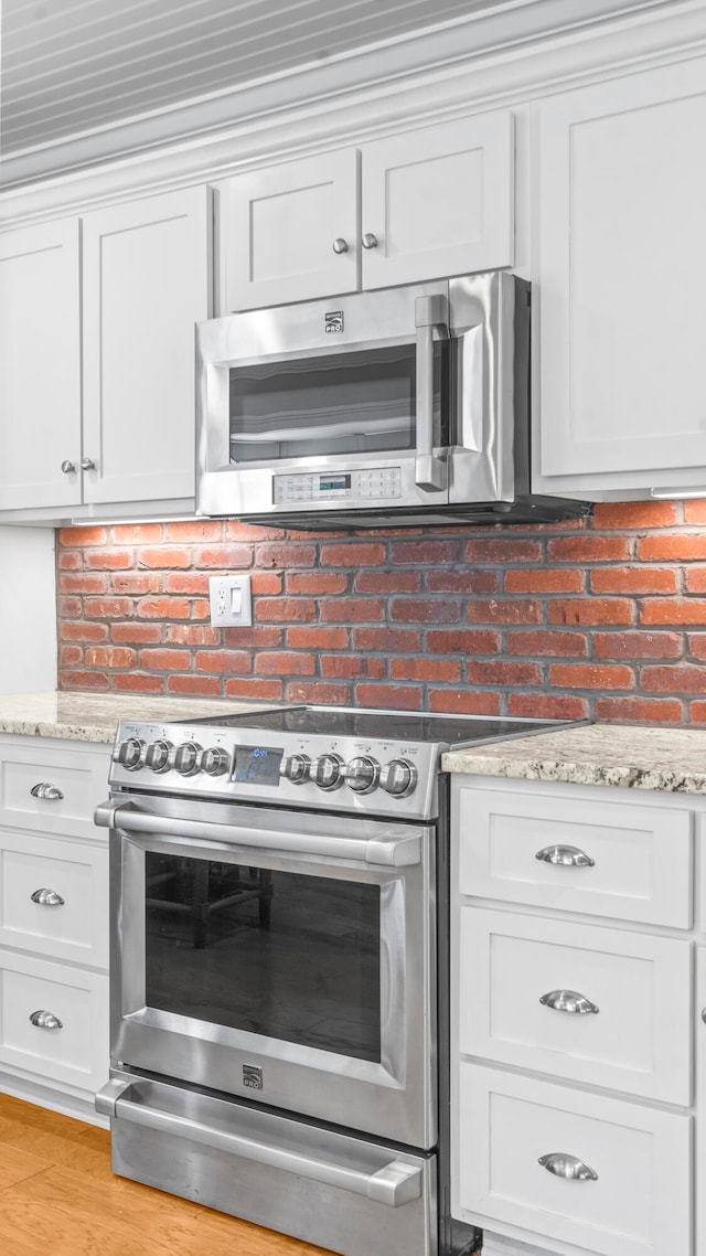 kitchen with light stone counters, white cabinets, and stainless steel appliances